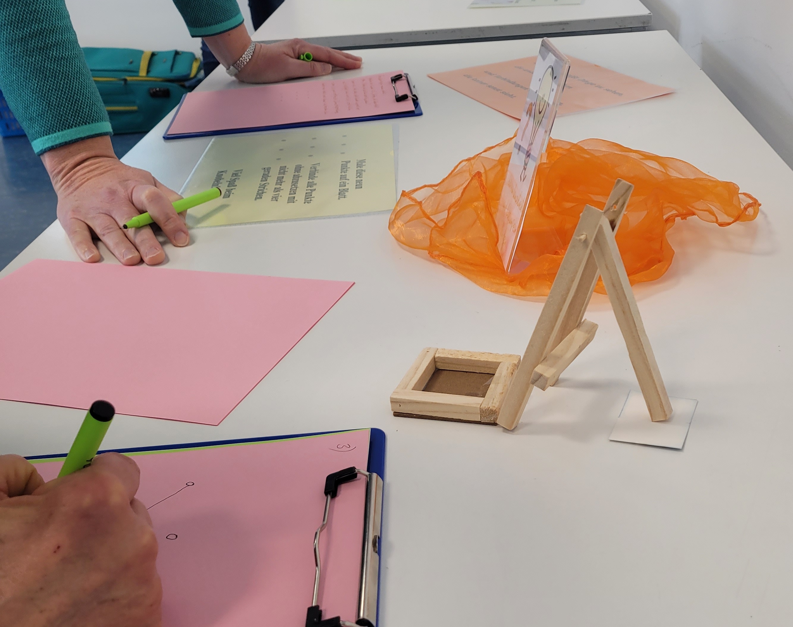 Utensilien und Hände mit Klemmbrett am Tisch